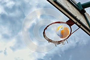 The ball flies into the basketball basket against a cloudy sky