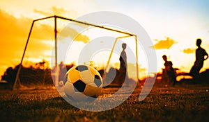 A ball on the green grass field for soccer football game under the sunset ray light and rain.Silhouette action sport picture.An ac