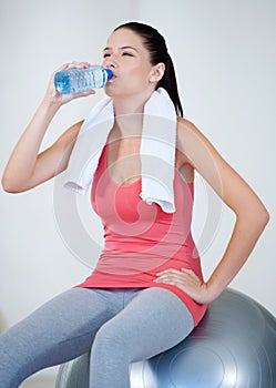 Ball, health or woman drinking water on break after exercise, workout or fitness training in gym. Thinking, tired lady