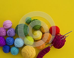 Ball for knit rainbow color a yellow background.