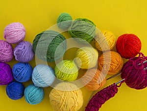 Ball for knit rainbow color a yellow background.