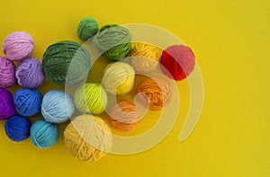 Ball for knit rainbow color a yellow background.