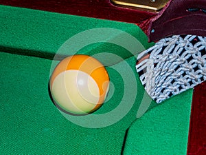 Ball near the pocket of the billiard table.