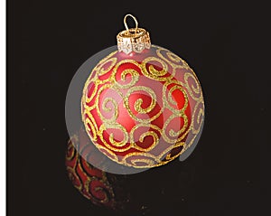 Ball ornament on black surface. Pick decor for christmas tree. Christmas ornament single red ball on black background