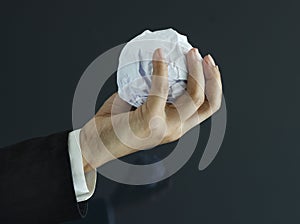 Ball of paper in hand on dark background, business concept