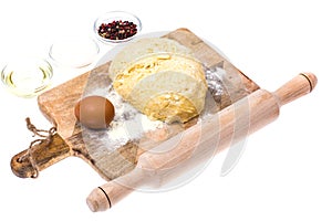 Ball of pizza dough on wooden kitchen cutting board with dusting of flour