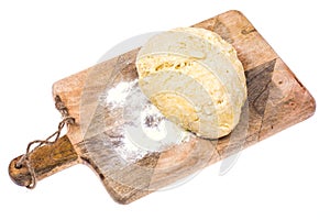 Ball of pizza dough on wooden kitchen cutting board with dusting of flour