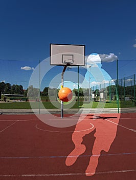 The ball in the player`s hands flies into the basketball ring on a sunny and clear day. Contour image of a basketball player. Mult