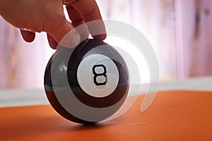 The ball of predictions figure eight on an orange background holds a hand