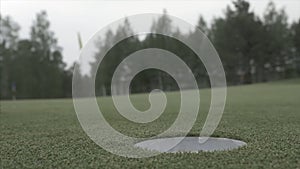 Ball rolling into the hole. Golf ball about to fall into a hole. Golf ball rolling into the hole on a gold course on a