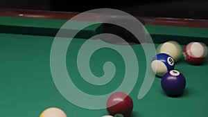 The ball is scored in the pocket. Sports game of billiards on a green cloth. Billiard balls with numbers on the billiard table