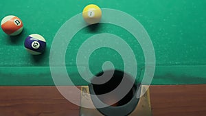 The ball is scored in the pocket. Sports game of billiards on a green cloth. Billiard balls with numbers on the billiard table