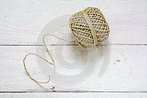 Ball of string with texture and strands on a white painted wooden background, copy space