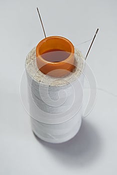 Ball of white thread with a needle on a white background