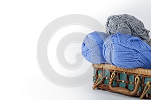 Ball of wool, needles and woolen sweater with spokes for handmade knitting in basket on wooden table