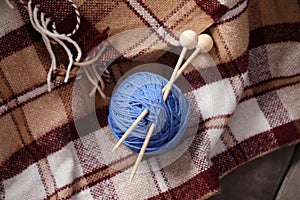 Ball of yarn with knitting needles on checkered plaid