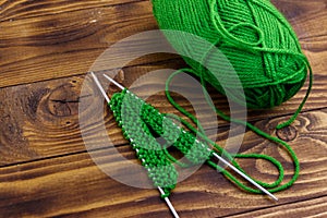 Ball of yarn and knitting needles with knitting on wooden table