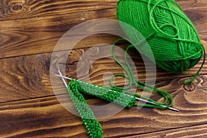 Ball of yarn and knitting needles with knitting on wooden table