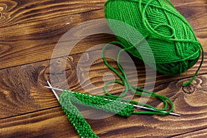 Ball of yarn and knitting needles with knitting on wooden table