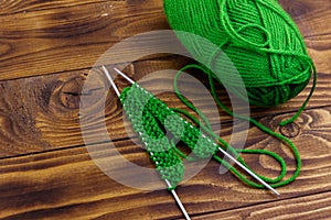 Ball of yarn and knitting needles with knitting on wooden table