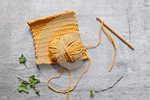 Ball of yellow yarn with crochet hook