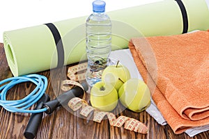 Ball, yoga Mat and water bottle close-up. Sports equipment, three green apples and a jump rope.