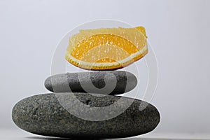 A ballans tower of grey stones and grapefruit orange fruit on a white yellow background with room for text. Benefits of Energy
