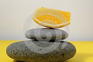 A ballans tower of grey stones and grapefruit orange fruit on a white yellow background with room for text. Benefits of Energy