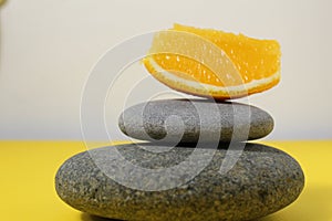 A ballans tower of grey stones and grapefruit orange fruit on a white yellow background with room for text. Benefits of Energy