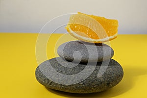 A ballans tower of grey stones and grapefruit orange fruit on a white yellow background with room for text. Benefits of Energy