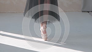 Ballerina in a black transparent skirt shows classic ballet pas. Ballet dancer`s feet as she practices pointe exercises