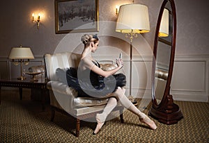 Ballerina in black tutu sitting in front of mirror