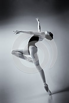 ballerina in a blue bodysuit and ballet shoes poses in a photo studio in motion showing beautiful long legs