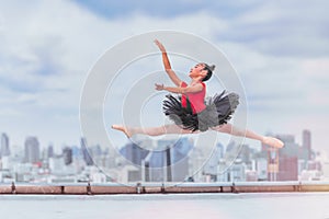 Ballerina dancer performing ballet dance on rooftop of building in city