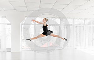 Ballerina dancer performing a jump in white studio