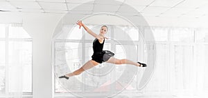 Ballerina dancer performing a jump in white studio