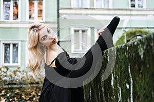 Ballerina Dancing in autumn city street, Modern Ballet Dancer in black dress, Pointe Shoes outdoors. Ballerina stretches