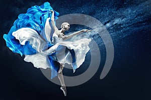 Ballerina dancing in Blue Chiffon Dress over Night Sky Background. Ballet Dancer jumping in fluttering Skirt pointing towards Hand
