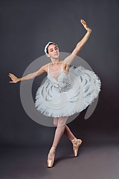 Ballerina dancing in white dress. Color photo. Graceful ballet dancer or classic ballerina dancing  on grey studio