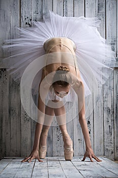 Ballerina dressed in white tutu makes lean forward