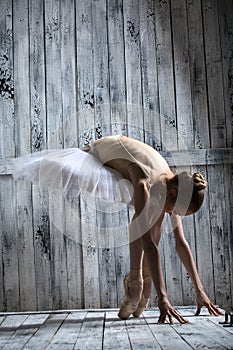 Ballerina dressed in white tutu makes lean forward