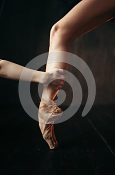 Ballerina hand holds the foot in pointe shoes