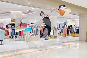 Ballerina leaping with shopping bags in the mall