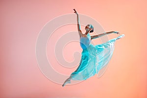 Ballerina in a light light dress flying in jump on an illuminated colored background