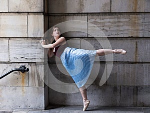 Ballerina in long pleated skirt and pointe shoes standing on fully extended foot