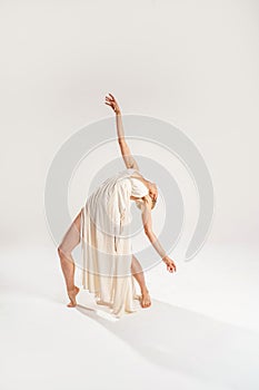 Ballerina in maxi dress dancing over light studio background. Ballet Dancer. Modern Dance. Graceful Woman