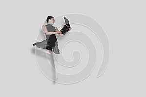 Ballerina performing jump with laptop on studio