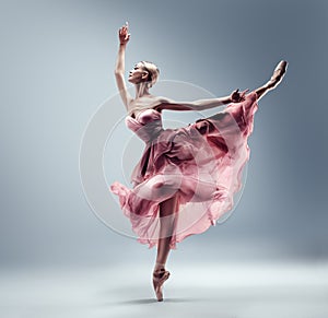 Ballerina in Pink Chiffon Dress jumping Split. Ballet Dancer in Silk Gown Pointe Shoes. Graceful Woman in Tutu Skirt dancing over