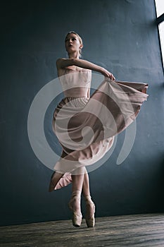 ballerina in a pink dress and punts moves around the room with a fluttering dress