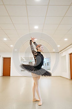 Ballerina poses at barre in class, ballet school